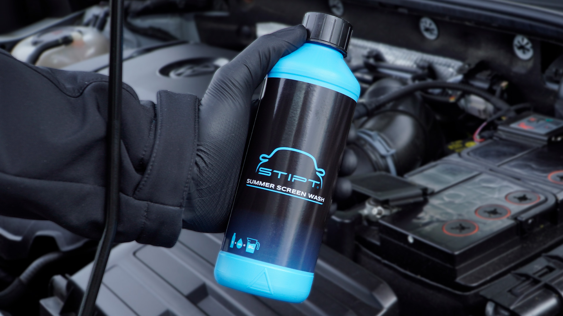 Stipt Summer Screen Wash fles in de hand bij de motorruimte van een auto