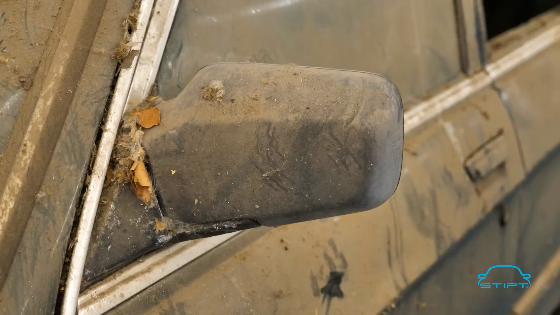Verweerde kunststof buitenspiegel van een auto vóór behandeling met Stipt Plastic Restore